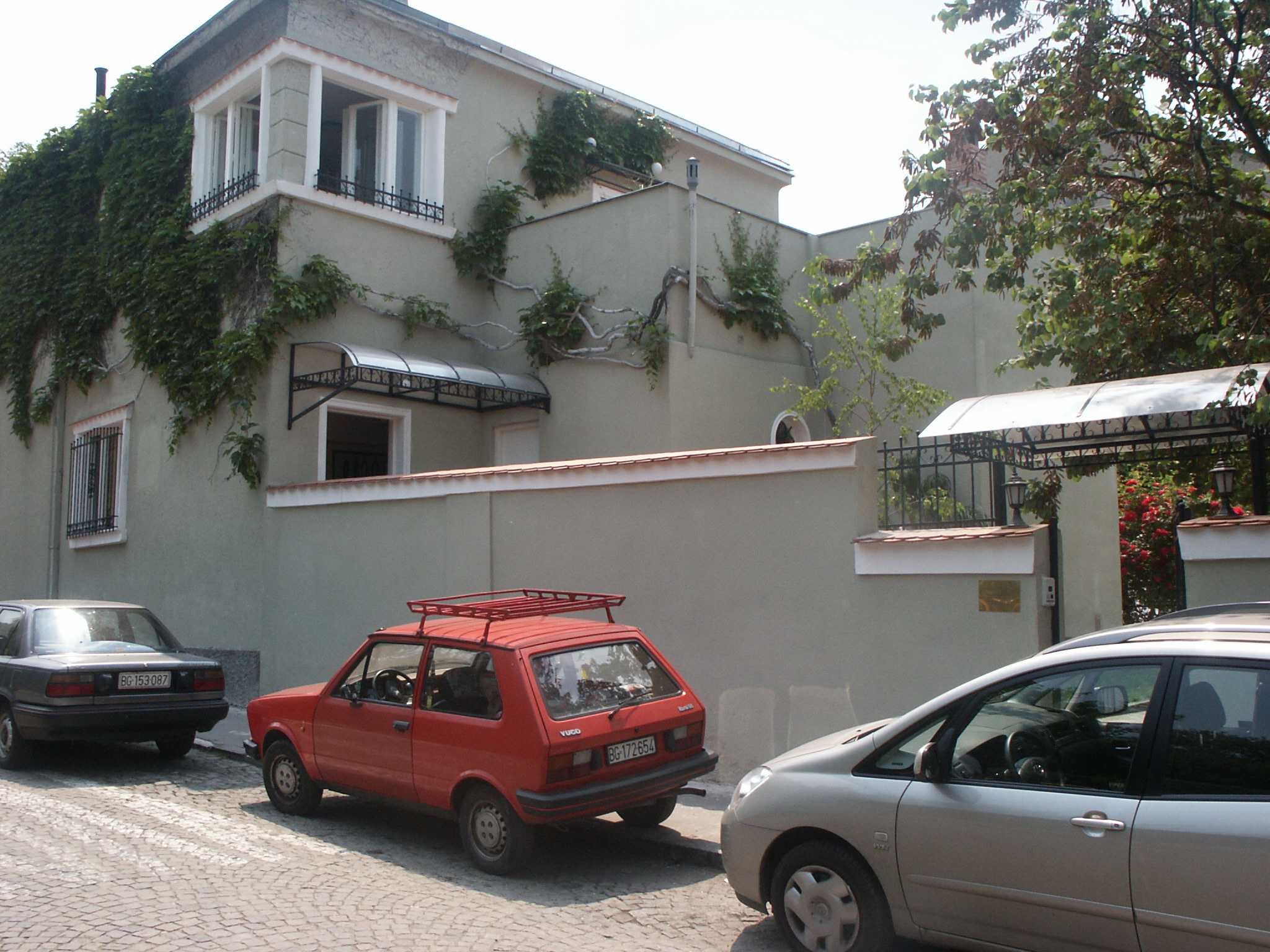 Street view of a stucco building with ivy and an awning, warm Mediterranean light
